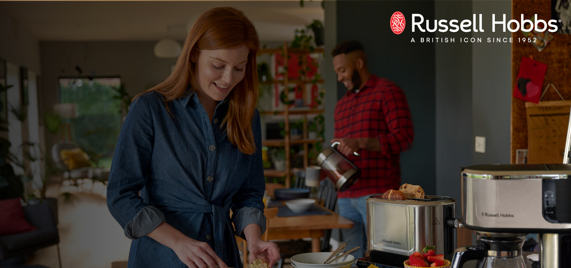 Woman preparing food in a kitchen with a man in the background, Russell Hobbs logo visible